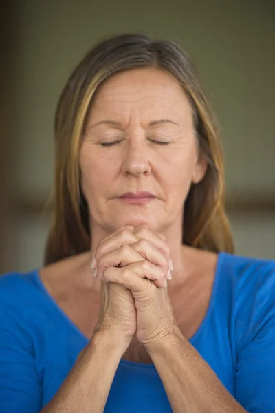 Woman praying with closed eyes concentrated