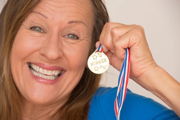 Joyful mature woman presenting medal