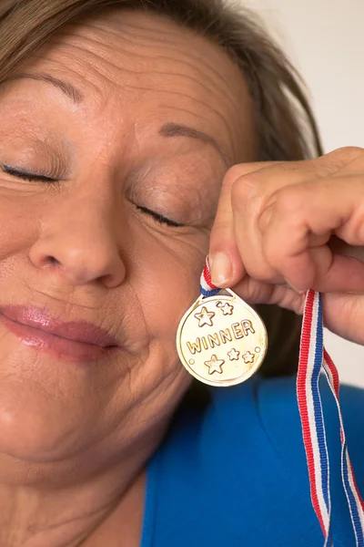 Proud mature woman presenting gold medal