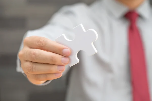 Businessman holding white jigsaw piece