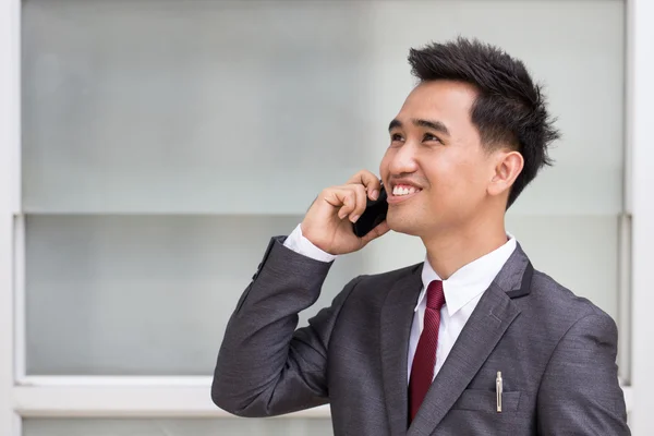 Asian businessman in suit speaking on the phone
