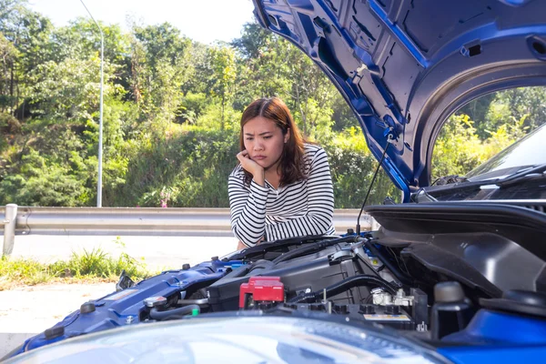 Asian women opened the hood and looking at broken down car engine