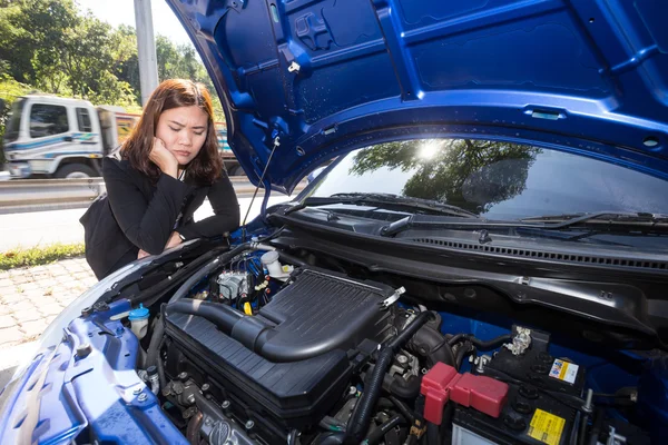 Asian women opened the hood and looking at broken down car engine on street