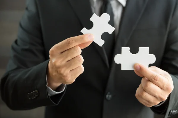 Businessmen holding two jigsaw to connect