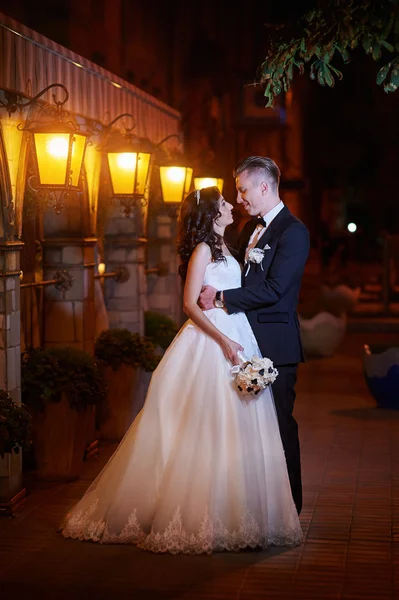 Bride and groom walk in city at night