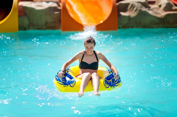 Beautiful young woman pulls off the slides in water park