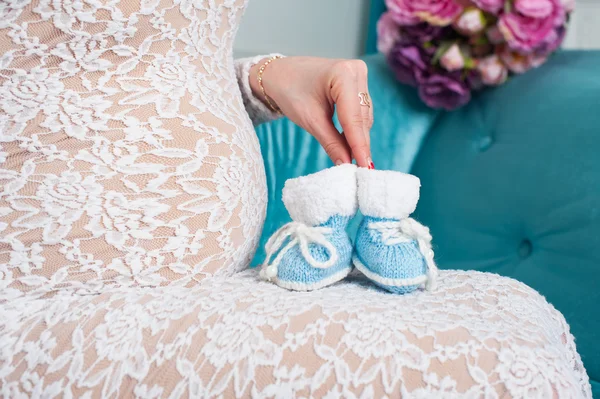 Pregnant mother holding little knit baby shoes