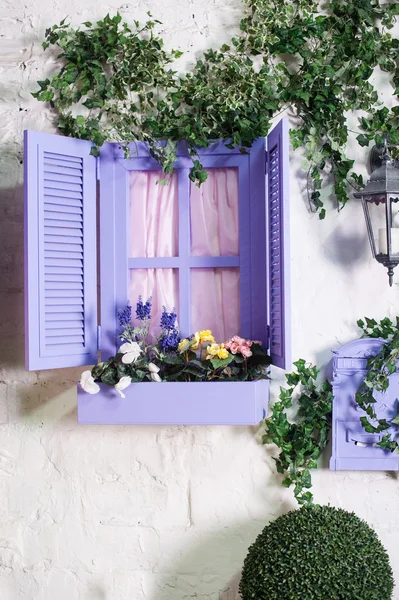 Pretty small purple window and box with flowers in an old house