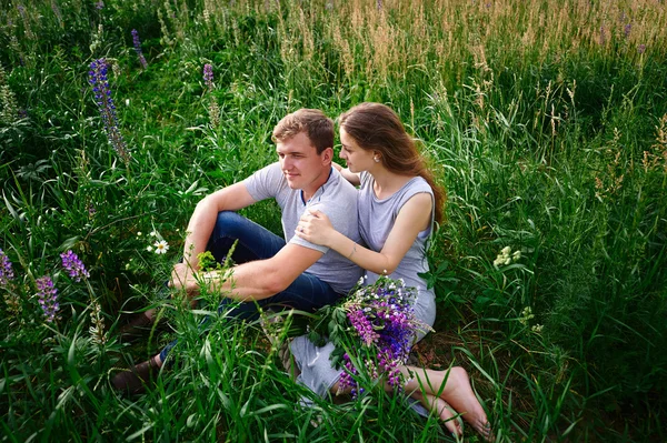 Couple in love sitting on green grass summer meadow