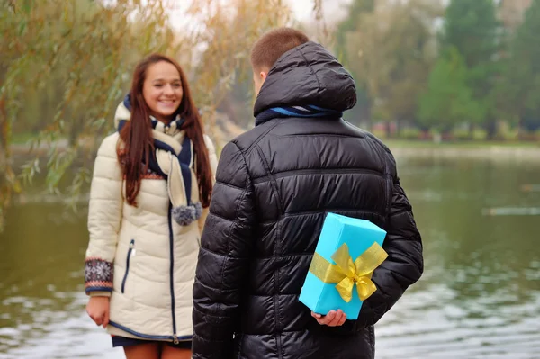 Back of a Japanese woman trying to pass a Christmas gift to man