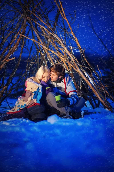 Couple in love at night, drink tea, it's snowing