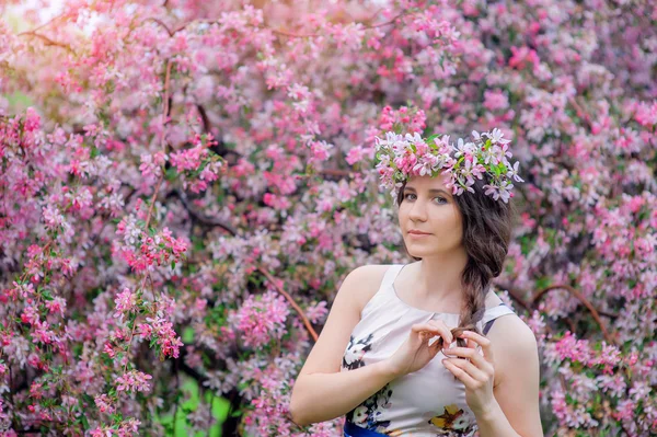 Young woman in the spring in the park with garlands of flowers