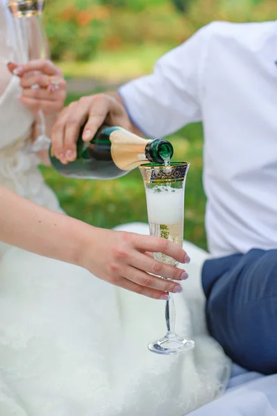 Groom pouring for bride champagne into the glass in the summer p