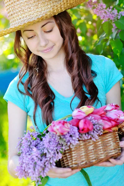 Beautiful woman in a straw hat with basket of flowers
