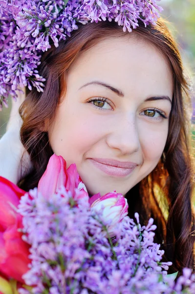 Beautiful girl with a bouquet of lilac walking in spring park