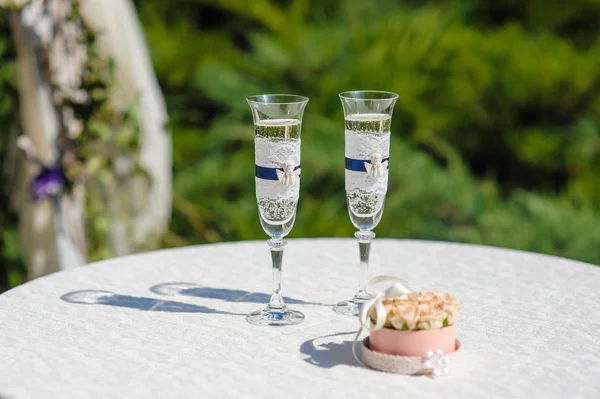 Two glasses with champagne and stand for rings
