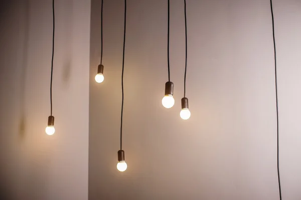 Many lamps on a long cord and hanging light in the room