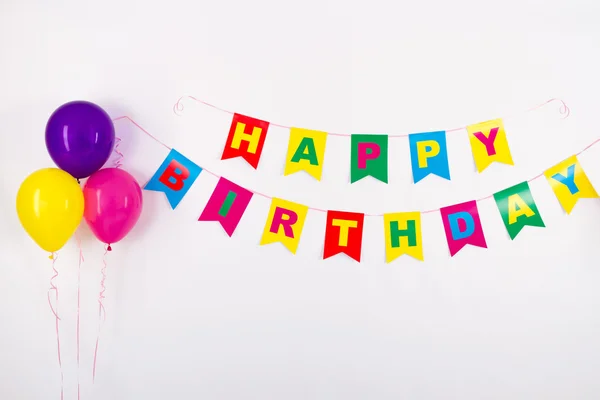 Colorful garlands, streamer, party hats and confetti. festive decoration background with sample text Happy Birthday