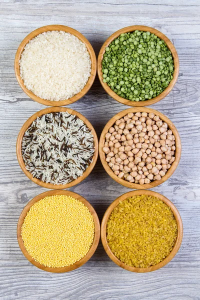Set of cereals, peas, rice, millet, chickpeas sprinkled in bamboo bowls on wooden background