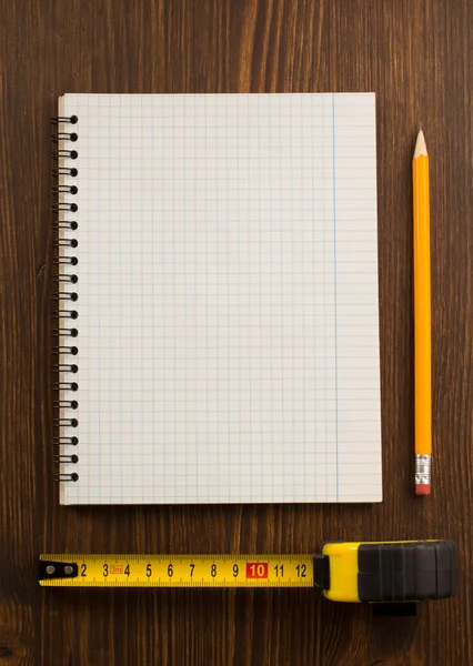 Tape measure and pencil with notebook