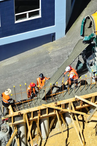 Builders pour cement to a concrete wall