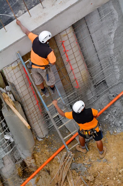 Manual workers inspecting a concert wall in construction site