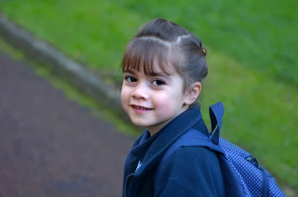 Happy little girl walks to school  looking back over her shoulde