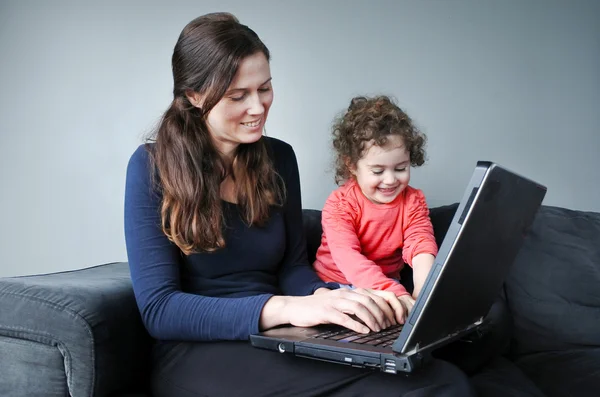 Happy mother with baby toddler works from home