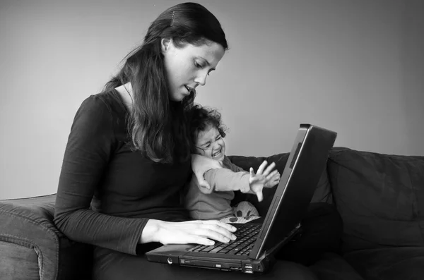 Stressed mother with baby toddler works from home