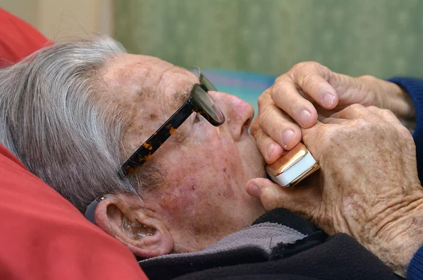 Old man plays harmonica
