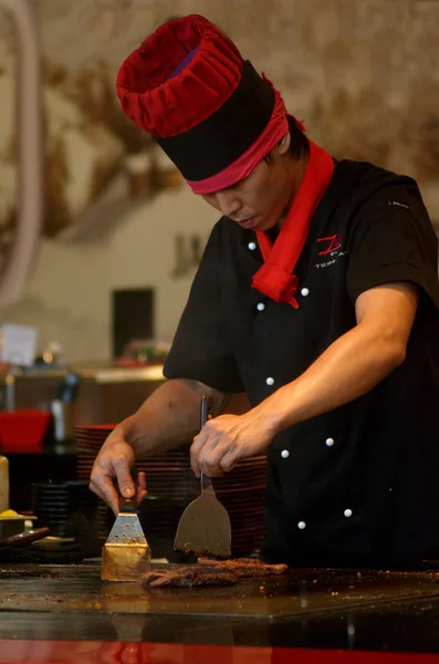 A teppanyaki chef cooking at a gas powered teppan