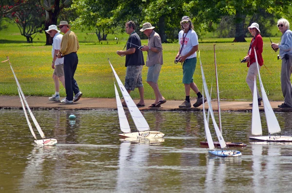 People racing remote control sailing wooden yachts