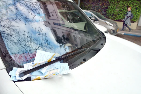 Parking ticket placed under windshield wiper of a car