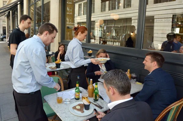 Waiters serving food and drinks to people dining in a restaurant