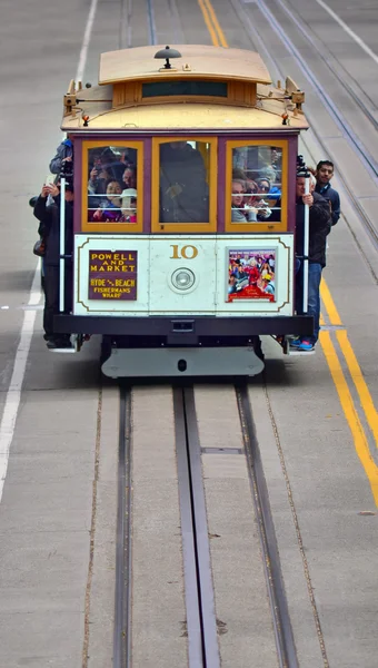 Passengers riding on cable car on steep hill in San Francisco, C
