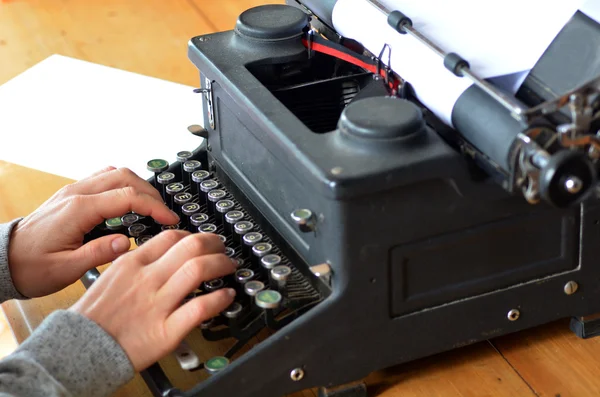 Hand of a young woman writer writing on antique typewriter