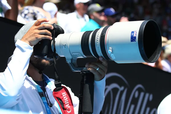 A photojournalist uses a Canon telephoto lens to capture action at Australian Open 2016