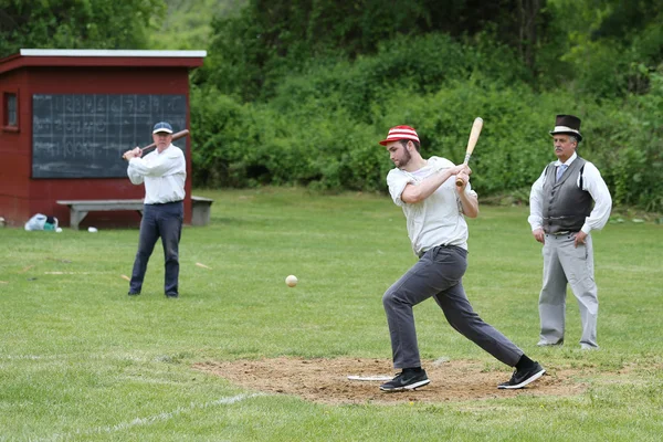 Baseball player in 19th century vintage uniform during old style base ball play following the rules and customs from 1864