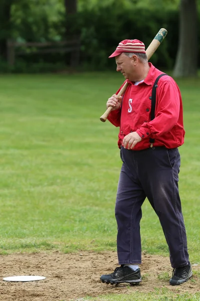 Baseball player in 19th century vintage uniform during old style base ball play following the rules and customs from 1864