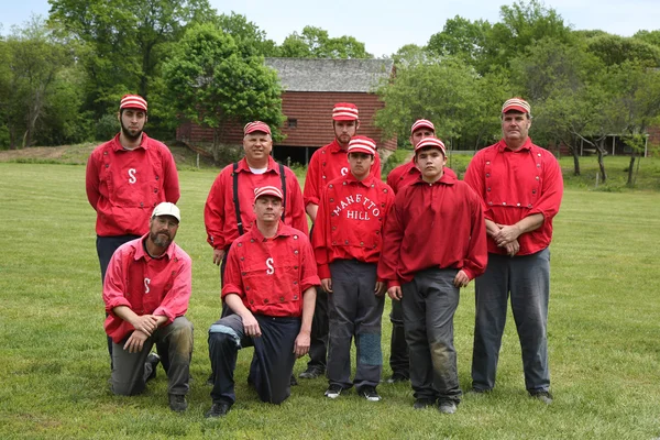 Baseball team in 19th century vintage uniform during old style base ball play following the rules and customs from 1864