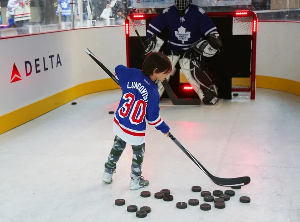 Young New York Rangers fan shooting the puck before Rangers season opening match at Madison Square Garden in NYC
