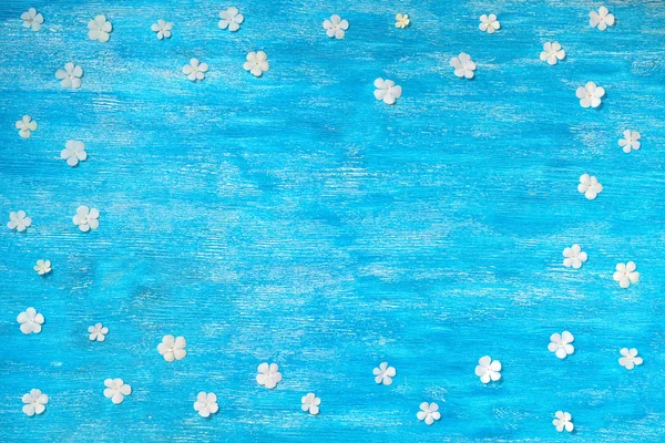 Beautiful border white flowers on blue wooden background, close