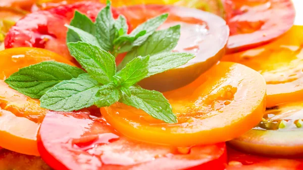 Colorful Tomato Slices with green branch of mint, Fresh Organic