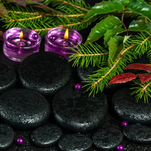 Winter spa concept of zen basalt stones with drops, lilac candle