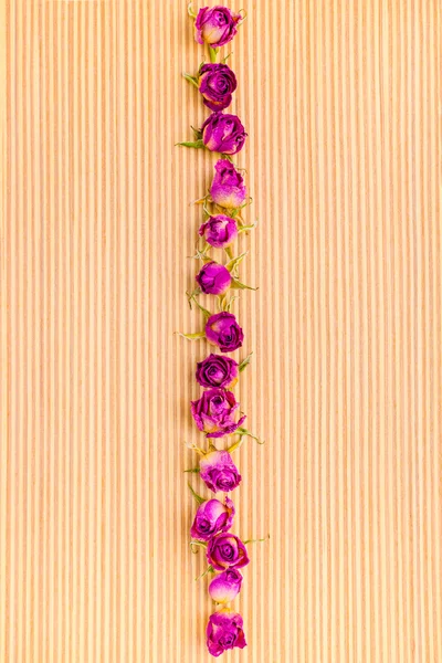 Frame of dried pink rose flowers on wooden striped background, c