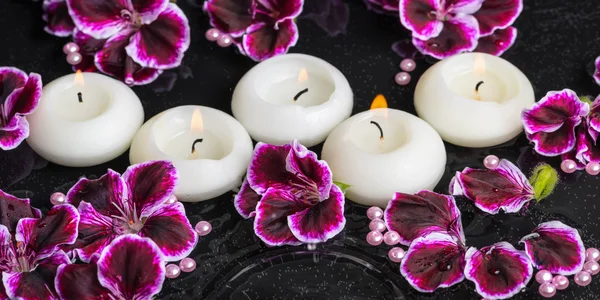 Beautiful spa still life of geranium flower and candles in rippl