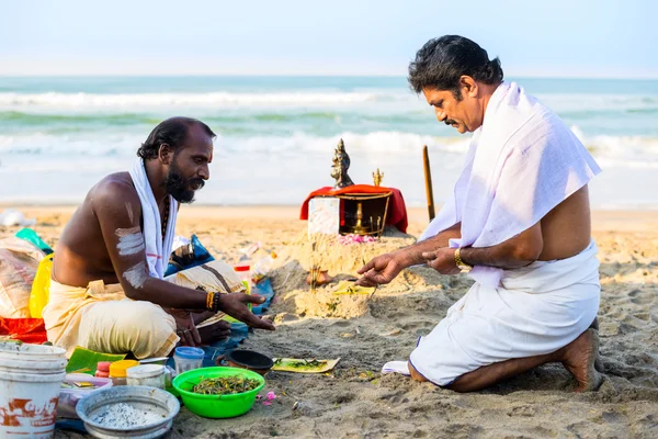 Hindu Brahmin with religious attributes providing ceremony and are blessing pilgrim