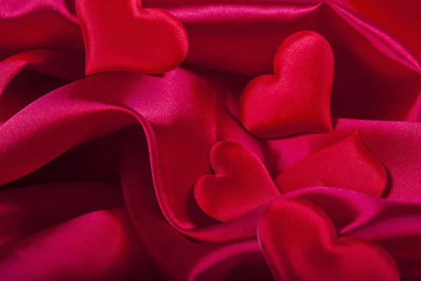 Red heart Valentine's Day symbols on red silk background close up