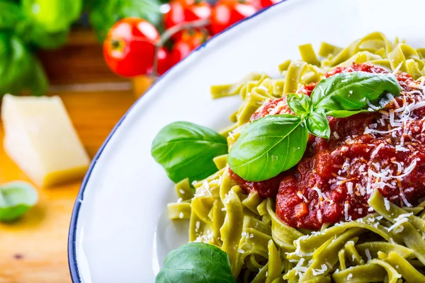 Pasta. Italian and Mediterranean cuisine. Pasta Fettuccine with tomato sauce basil leaves garlic and parmesan cheese. An old home kitchen with old kitchen utensils. Portion of on a fork pasta with tomato sauce and basil leaves