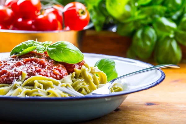 Pasta. Italian and Mediterranean cuisine. Pasta Fettuccine with tomato sauce basil leaves garlic and parmesan cheese. An old home kitchen with old kitchen utensils. Portion of on a fork pasta with tomato sauce and basil leaves